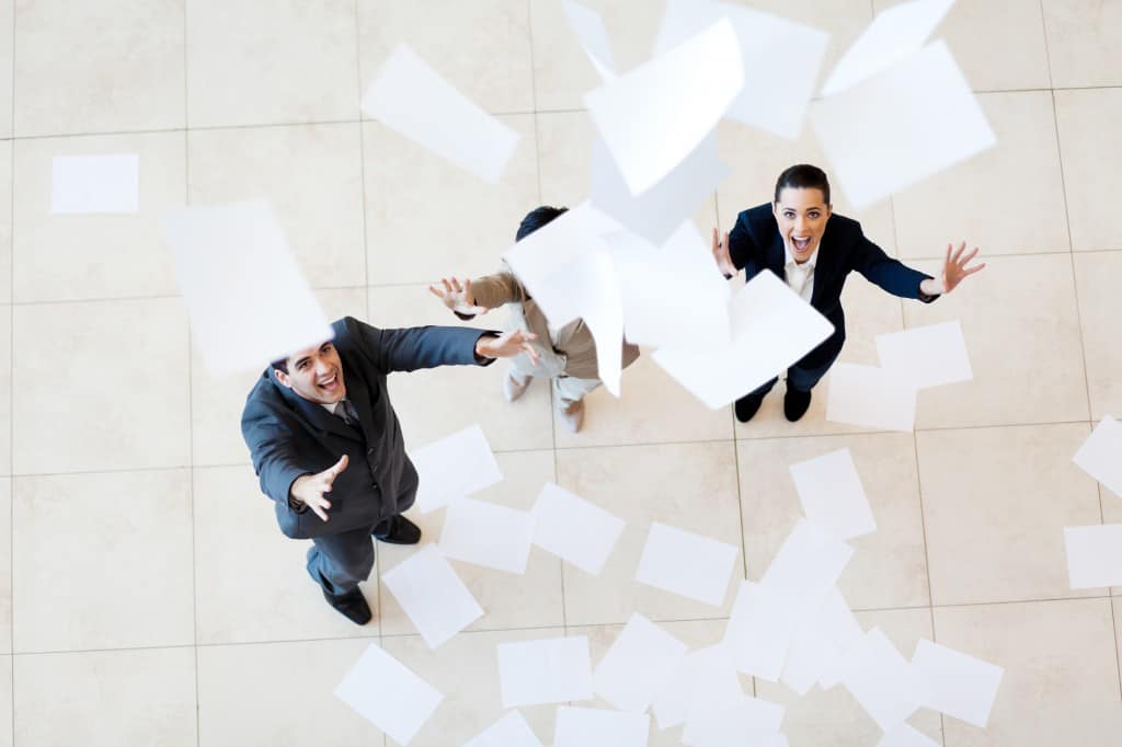 Happy businesspeople throwing papers in the air for celebration.